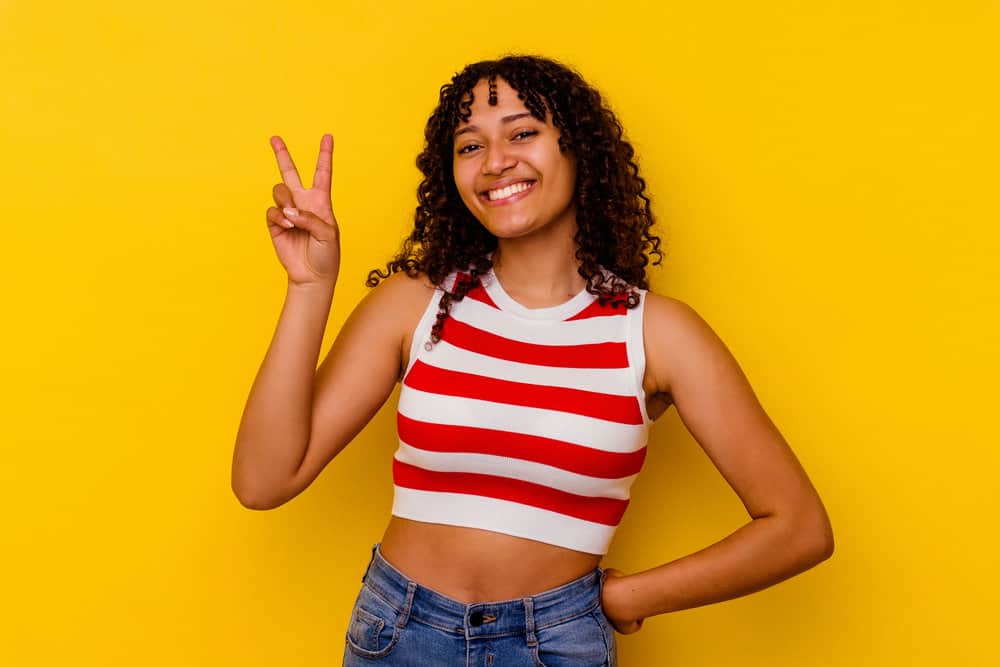 A mixed-race female with a higher curl pattern is wearing her natural hair in a loose style that highlights her curl type.