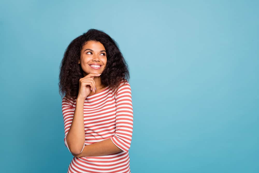 A young black lady with type 3 natural hair styled in a layered hair-cut that's starting to experience damaged ends.