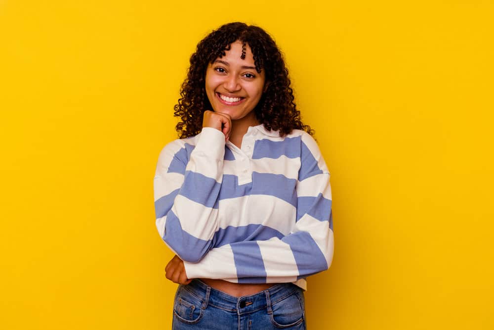 A cute African American lady with curly baby hair strands showing hair regrowth while her scalp itches.