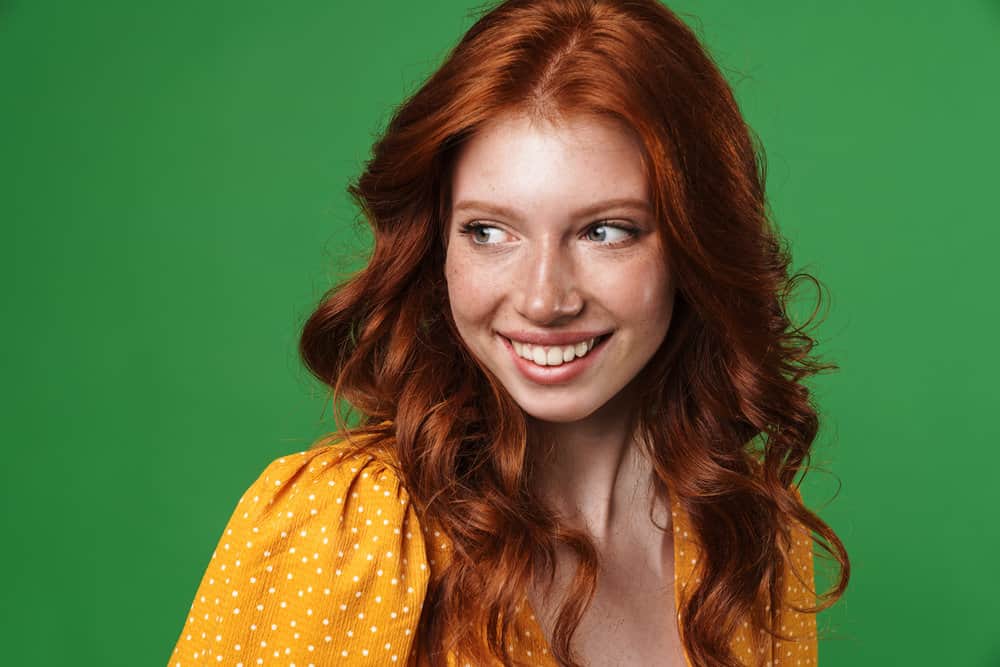 A female with naturally red hair with orange tones styled with coconut oil, highlighting the orangish-red undertones. 