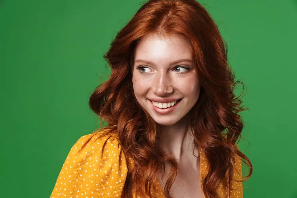 Why Is My Hair Turning Red Naturally? Becoming a Redhead? 3 A female with naturally red hair with orange tones styled with coconut oil, highlighting the orangish-red undertones.