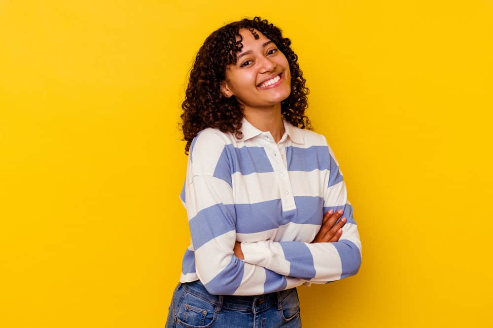 A cute mixed-race female with curly hair styled with tea tree oil after being washed with a thorough shampoo scrub.