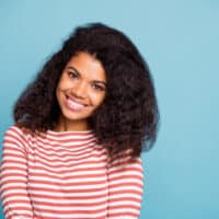 A cute black woman with healthy hair strands after getting her 3B hair type trimmed to mitigate split-end issues.