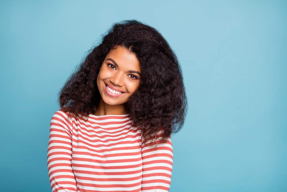 A cute black woman with healthy hair strands after getting her 3B hair type trimmed to mitigate split-end issues.