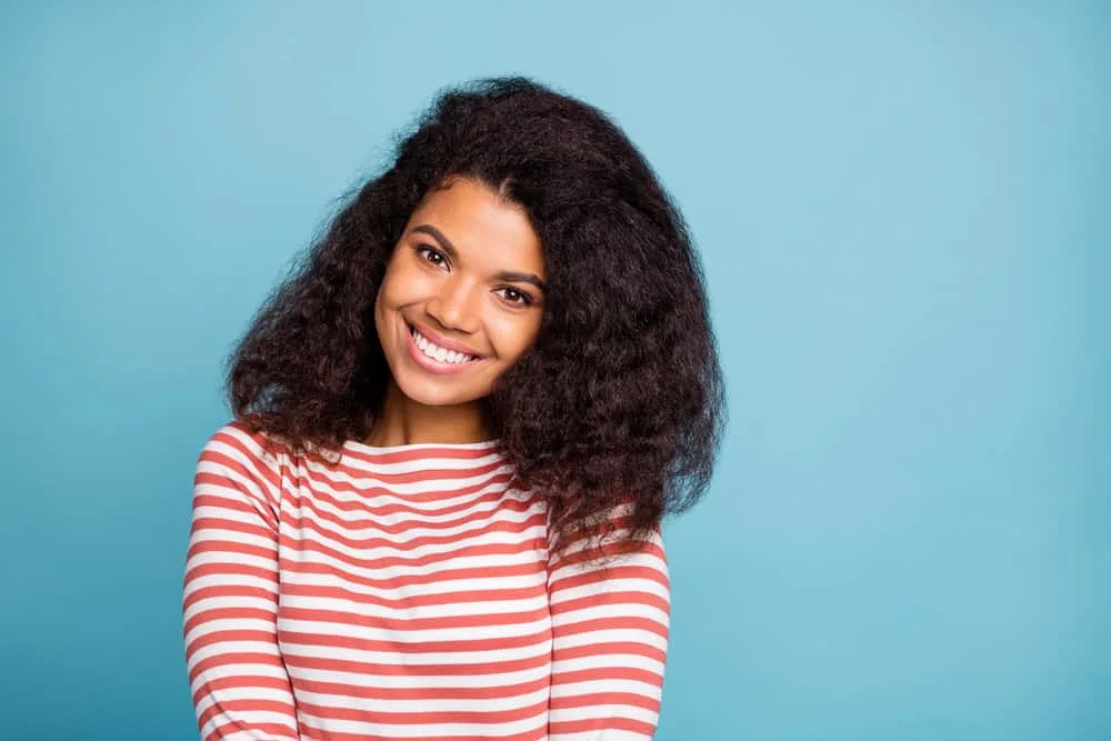 How Much Hair Is Cut Off in a Trim and Signs You Need a Trim 1 A cute black woman with healthy hair strands after getting her 3B hair type trimmed to mitigate split-end issues.