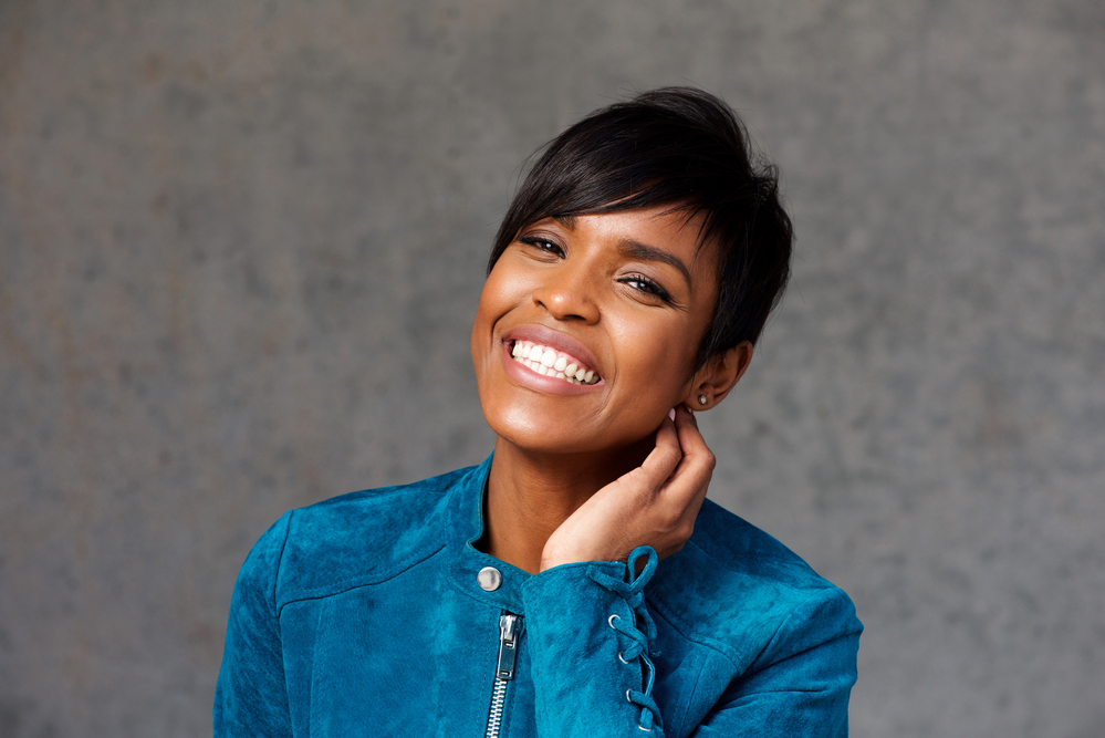 A beautiful black female with healthy hair follicles uses an air-drying process to dry her wet hair (or damp hair).