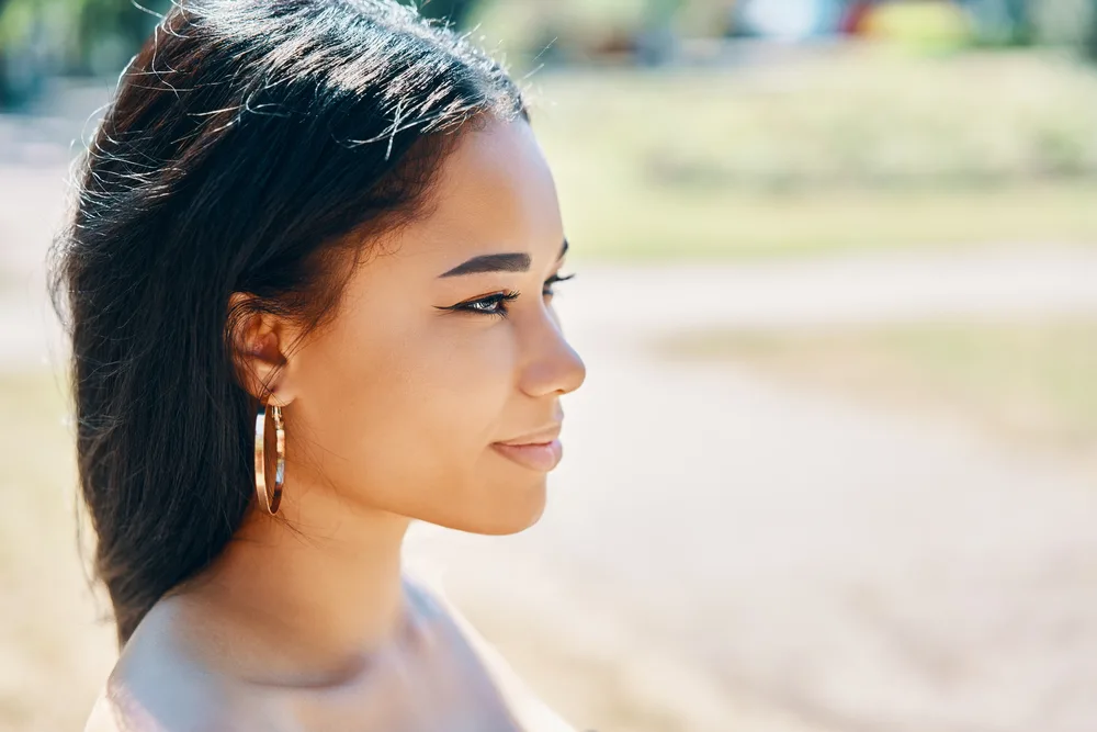 Does Blow Drying Your Hair Damage It? Should You Air Dry? 6 A beautiful African woman with stunning skin wearing neutral makeup, including eyeshadow, with her eyebrows arched.