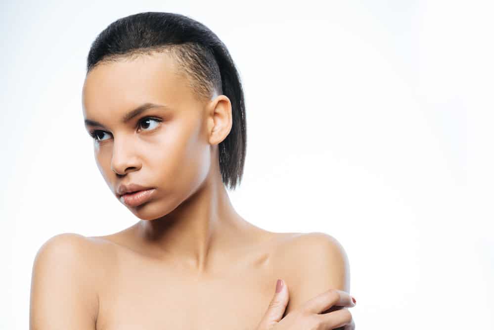 An elegant young female is wearing a classic mullet haircut on her longer hair, creating a punk vibe like Miley Cyrus.