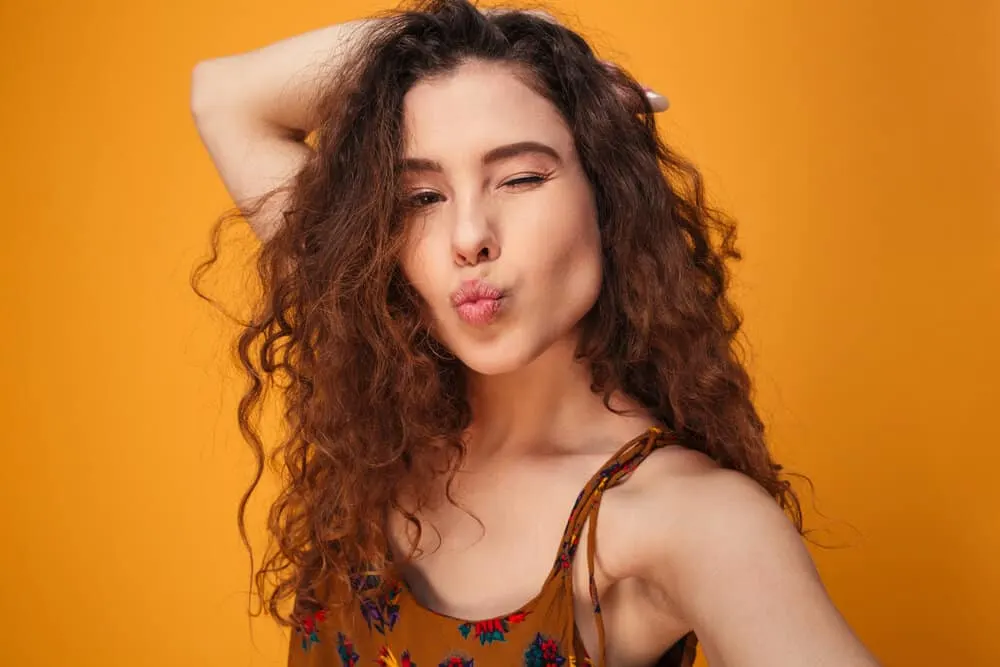 How to Get Messy-Looking Hair for Girls & Guys: Step-By-Step 9 A flirty young female with ombre curls is taking a selfie photo admiring the volume on her messy locks.