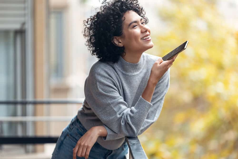 A black female is talking to a friend about experiencing mild female pattern hair loss after using a low-heat flat iron.