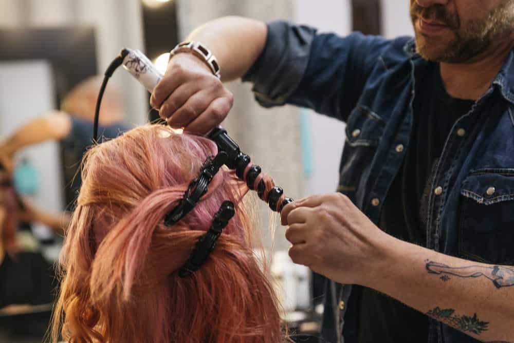 A savvy stylist that's new to the profession in his own salon doing a lady's hair who's a new member of his client base. 