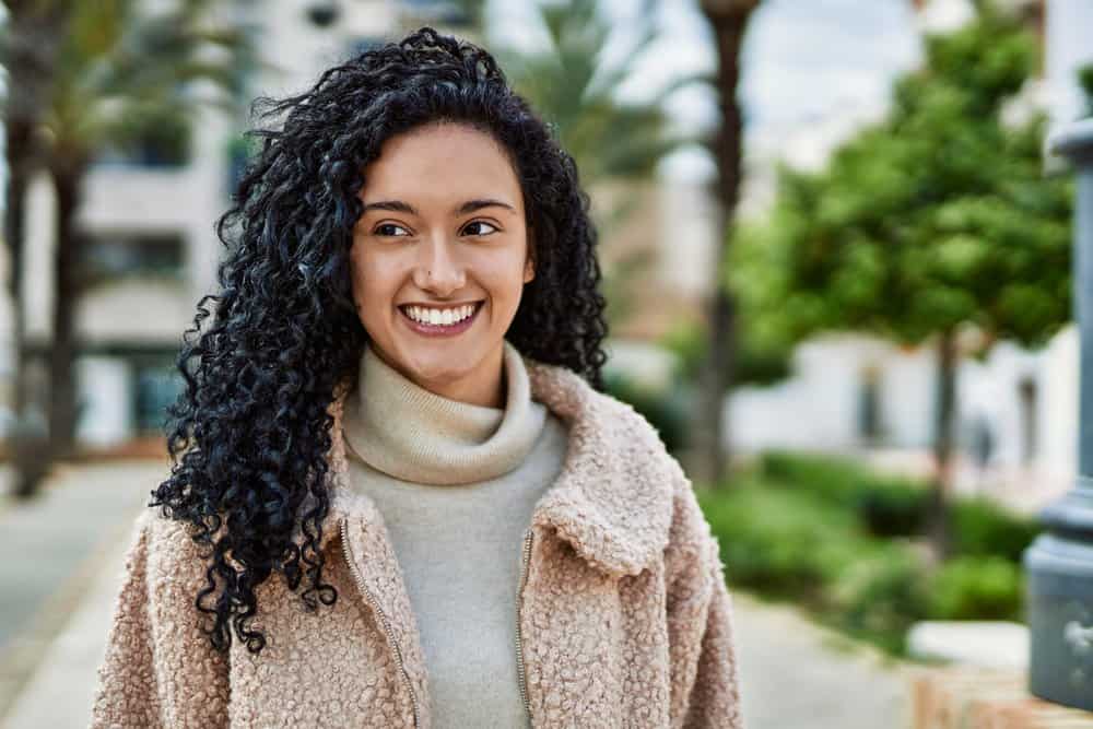 A confident female with a great smile at the mall about to purchase some more face makeup for light brown skin.