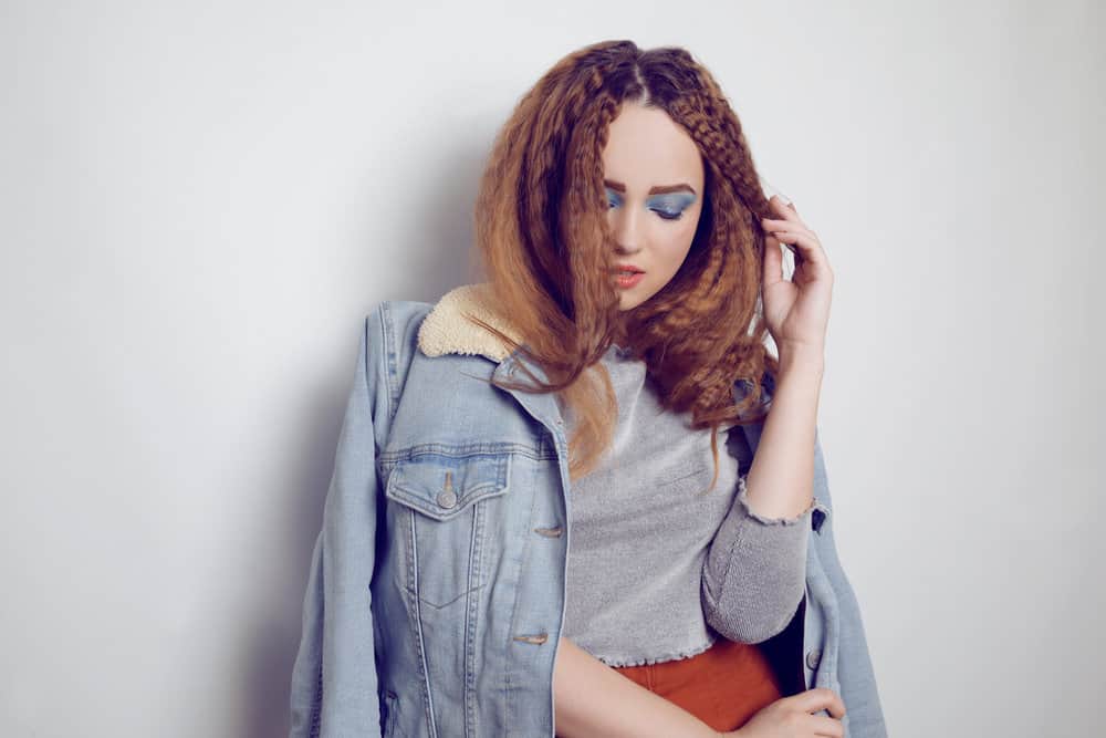 A girl with voluminous brushed hair has tight crimps after braiding her long hair, starting with the top half.