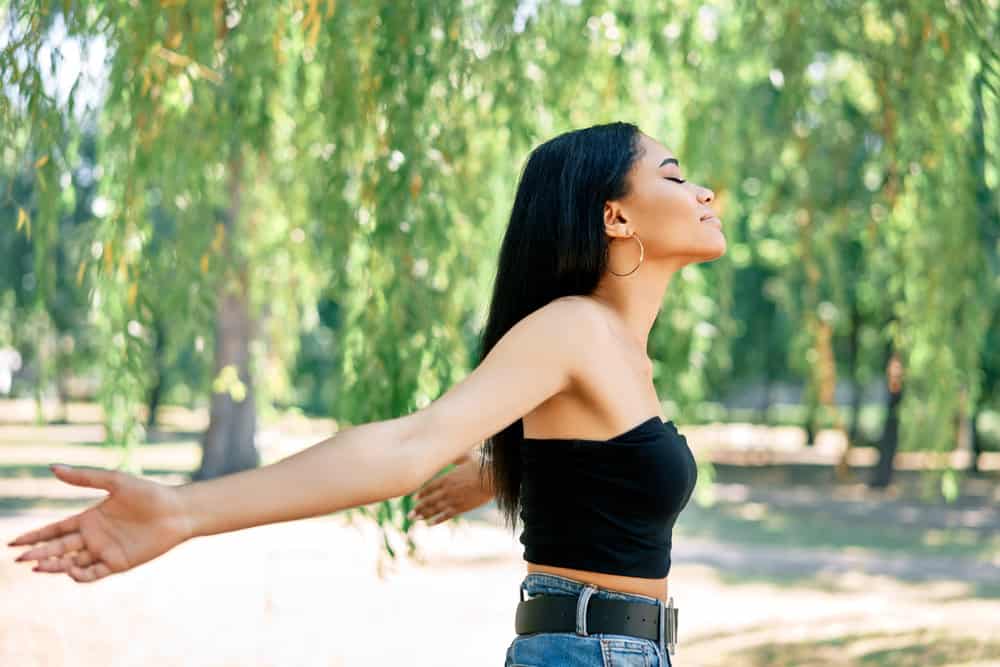 A lady outdoors at a local park enjoying the sunshine styled her straight hair with a round brush after applying heat.