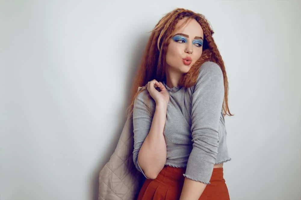 How to Crimp Hair With and Without a Crimper: Step-By-Step 11 A cute white female crimped her hair with a flat iron before letting her hair cool while wearing a stylish outfit.