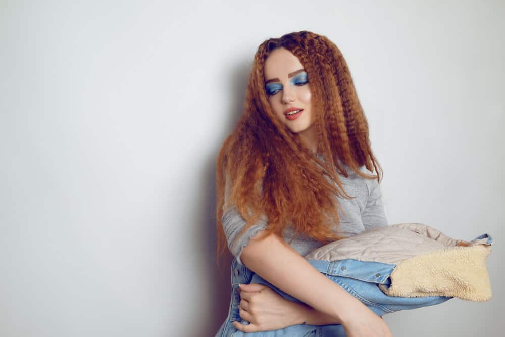 A young stylish model with bright blue makeup is wearing an 80s crimped hair style secured with u pins.