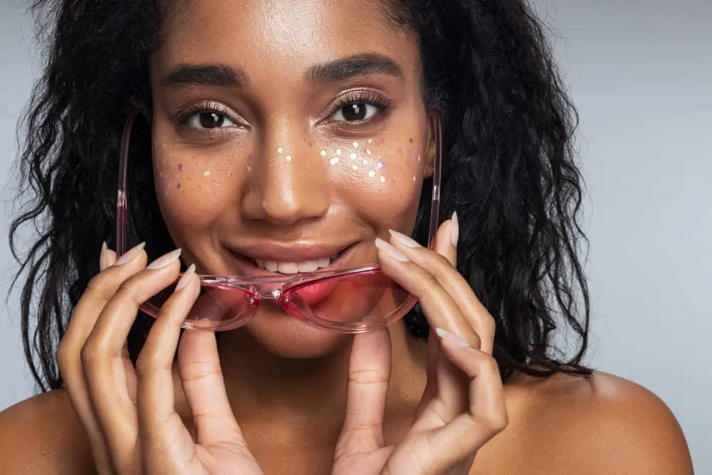 A cute black woman with oily hair after using a protein hair mask on her dry and damaged hair follicles.