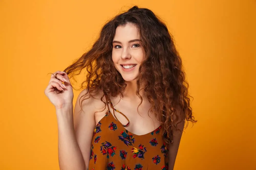 How to Get Messy-Looking Hair for Girls & Guys: Step-By-Step 4 An attractive female with an edgy, dark brown hairstyle and a light brown summer dress with colorful flowers.