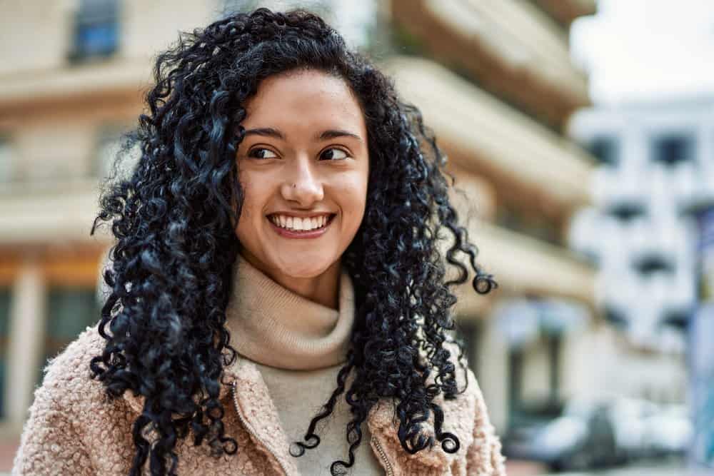 A woman with light brown skin created a unicorn haircut by point-cutting her dark brown, naturally curly hair.