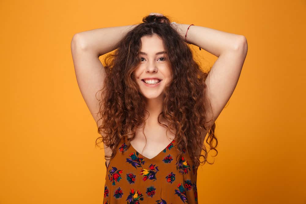 A cute young female with curly long hair with a wild, messy hair-look from over-shampooing.