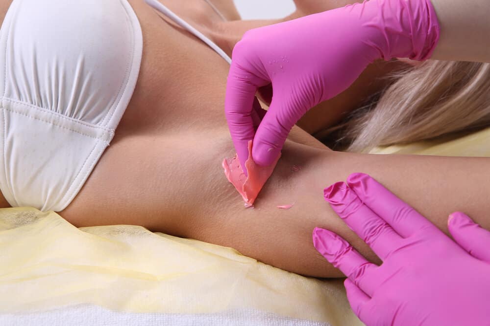 A Wax Specialist removes all the fine hair strands underneath a client's arm to prevent ingrown hairs.