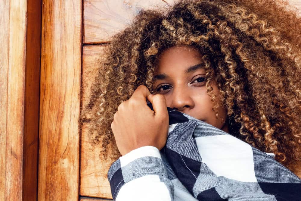 A cute black woman with long hair on a 3C hair texture is posing for a photo showing off her thick hair type.