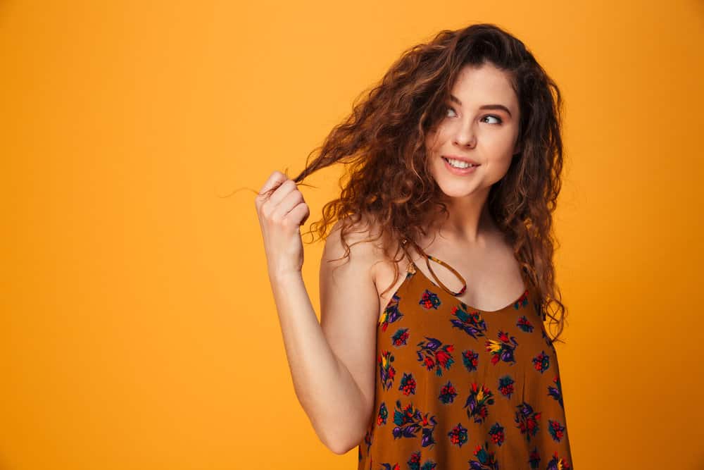 A cute young lady wearing a casual summer dress has beautiful light and dark brown dyed hair and smooth skin.