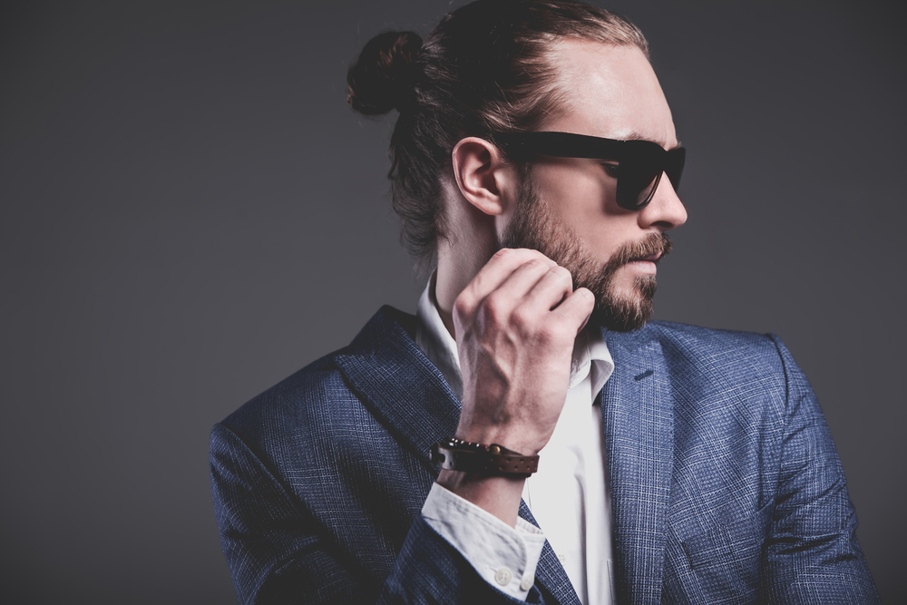 A handsome white guy wearing a man bun hairstyle in a half-up top-knot style secured with elastic band hair ties.