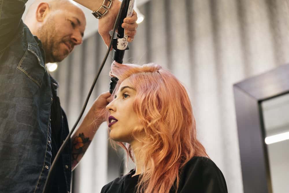 A cute female with a dark pink hair color getting her hair curled at a local hair salon in Birmingham, Alabama.