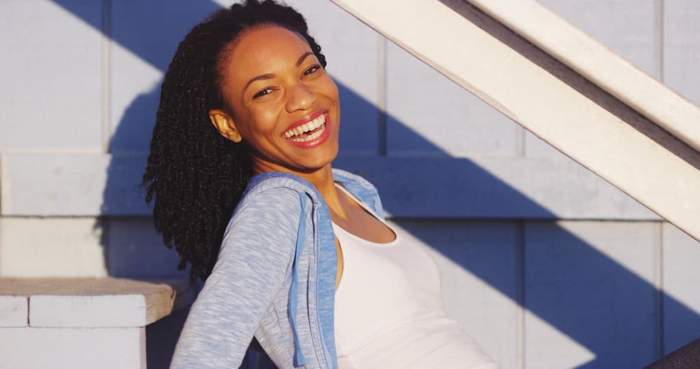 A light-skinned black lady wearing a delicate hairstyle made thicker with tangle-free synthetic hair extensions.