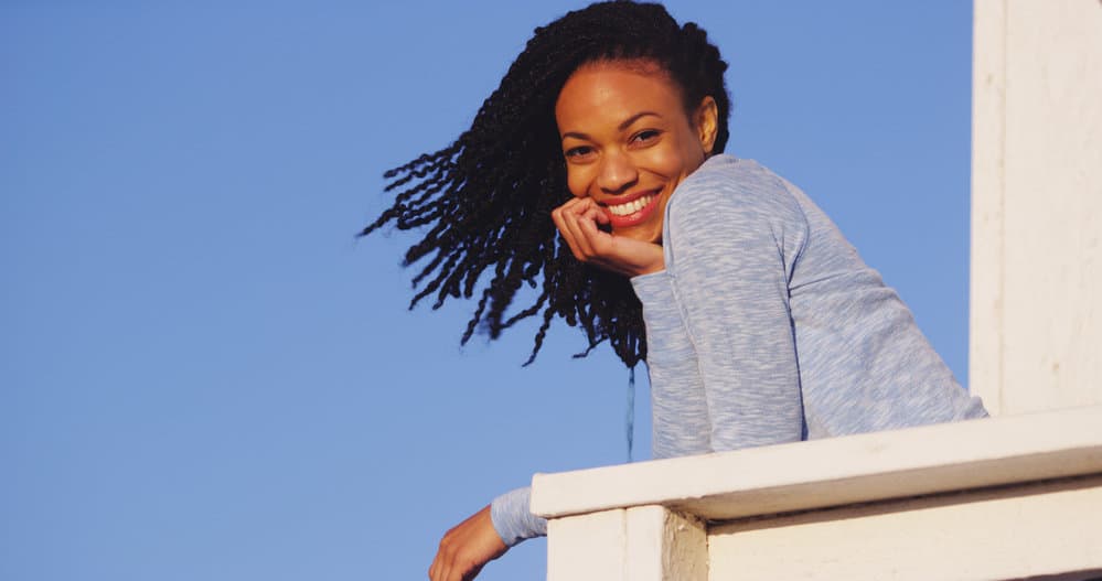 A cute black woman with a twist-out hairdo moisturized with styling cream, chemical-free products, and mineral oils.