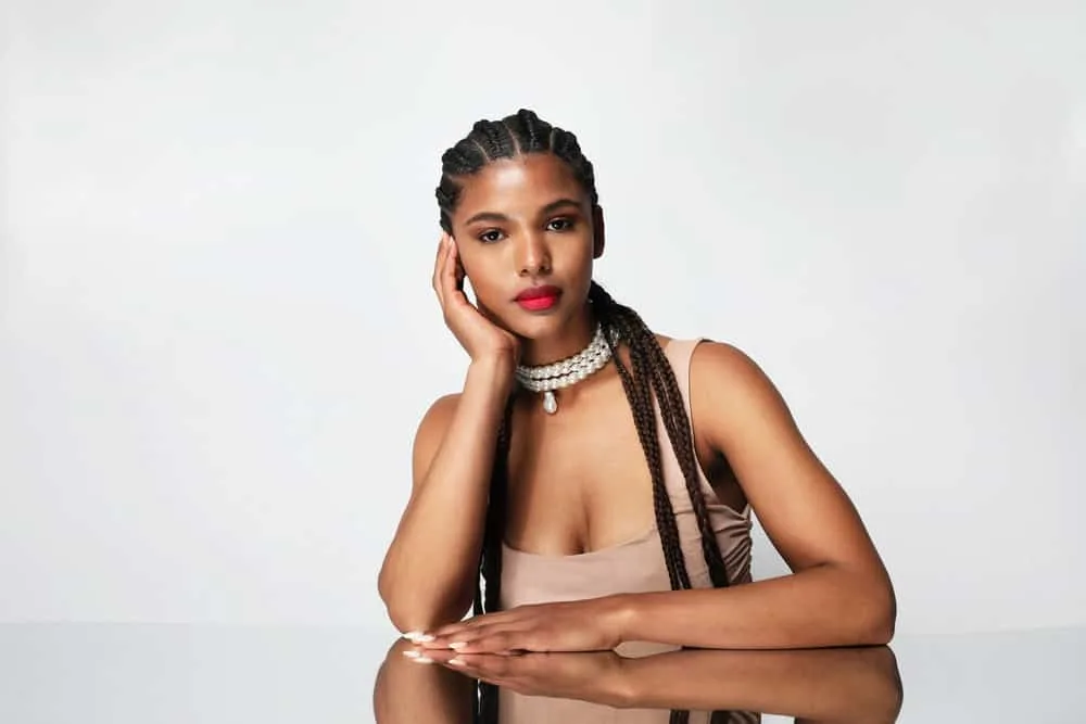 Box Braids vs. Cornrows: Which Is Better? What’s the Difference? 7 African American young woman with dark brown type 4 hair is wearing a long cornrow style with added hair.