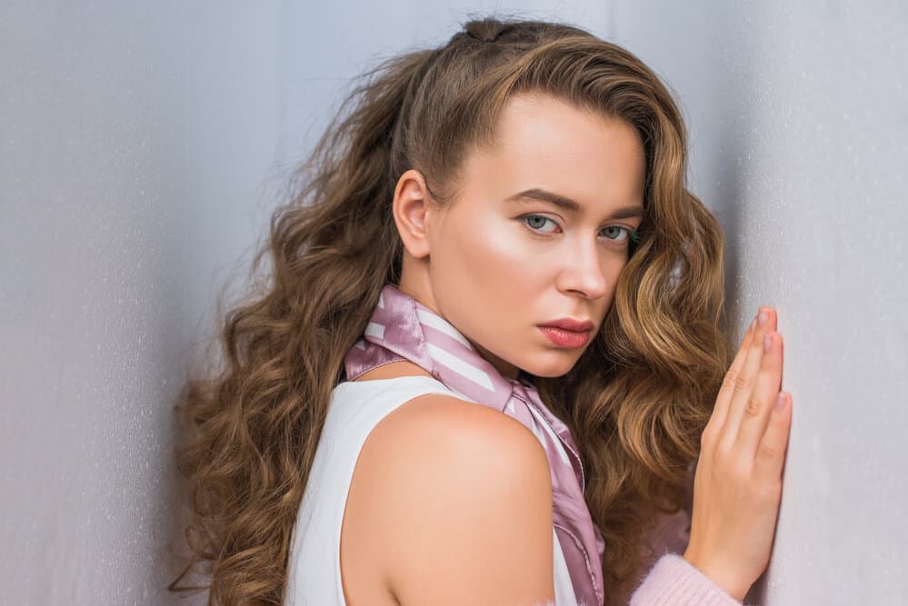 A female model with naturally curly hair after blow drying her straight hair used curling wands to make defined curls.