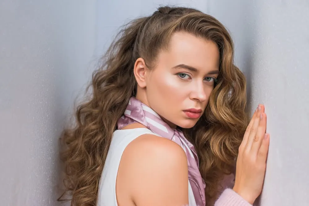 How to Use a Curling Iron on Yourself: DIY Step-By-Step 4 A female model with naturally curly hair after blow drying her straight hair used curling wands to make defined curls.