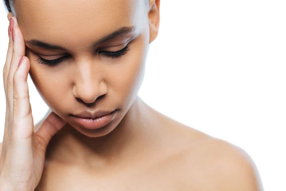 A calm black woman is wearing a country mullet haircut with a longer length than normal on her hair type.