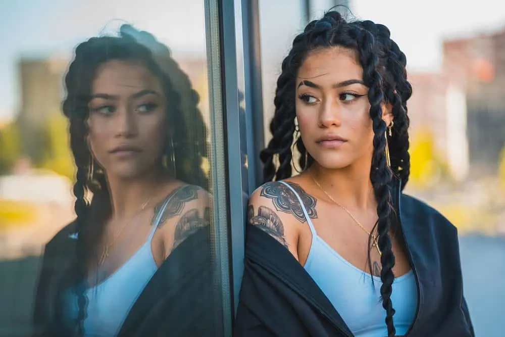 Why Your Hair Feels Thin After Braids and Is Thinning Normal 6 A fine young woman with beautiful olive skin and flower shoulder tattoo wearing her black hair in rope braid hairstyle.