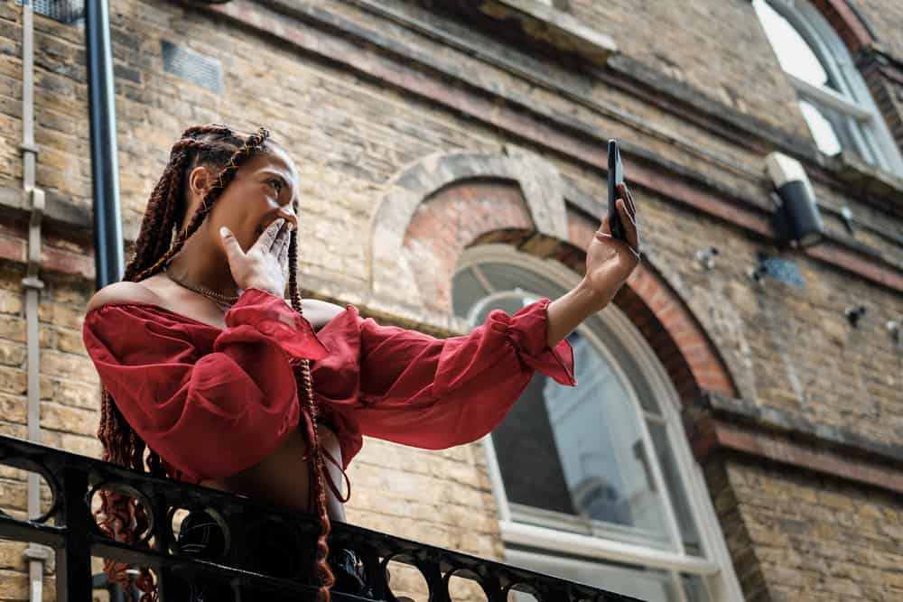 African American female that's wearing braids showing off her braided hair to family and friends with a selfie.