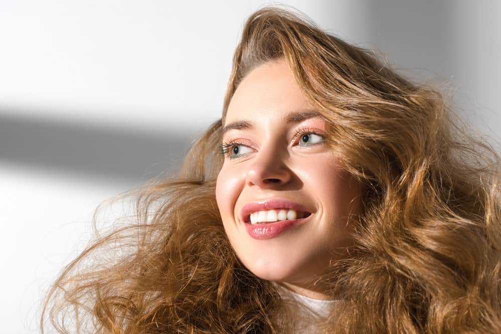 A young female that used a creative curl wand to curl hair creating a tighter curl on her thicker hair strands.