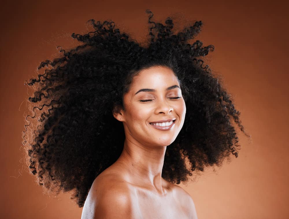 A black woman with naturally curly fine hair styled with coconut oil and a leave-in conditioner to make her hair shinier.