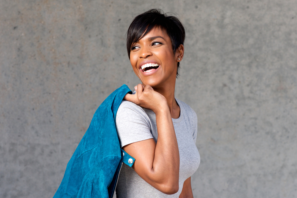 A light-skinned young black female wearing a gray t-shirt after using a paper towel to help her damp hair dry faster.