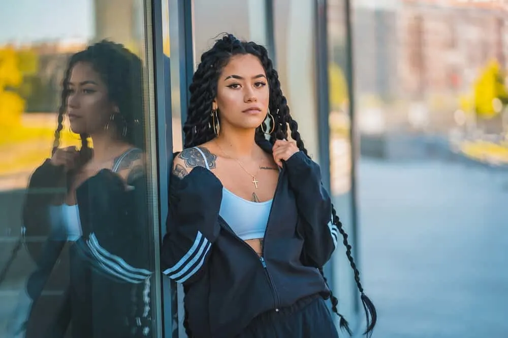 Why Your Hair Feels Thin After Braids and Is Thinning Normal 4 A young black female with thick, dark black roots in a braided protective style moisturized with a rehydrating mist.
