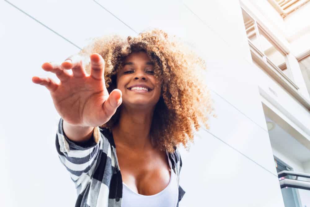 A joyful black female with dry hair just scheduled weekly salon visits for more maintenance to repair hair shaft damage.