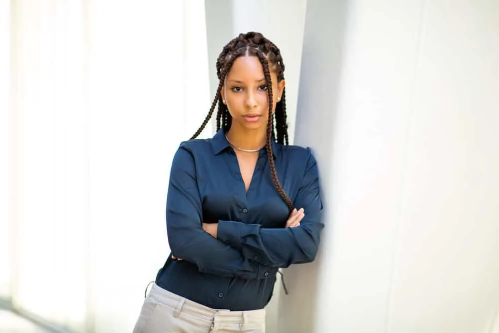 The 10 Best Summer Protective Hairstyles for Natural Hair 9 A confident professional black woman wearing a blue dress shirt and gray pants with Marley twists braids.