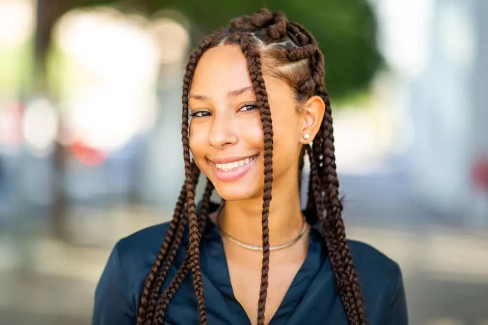 A black girl is wearing box braids with her baby hair slicked against her forehead with an attractive Nike-like swosh.