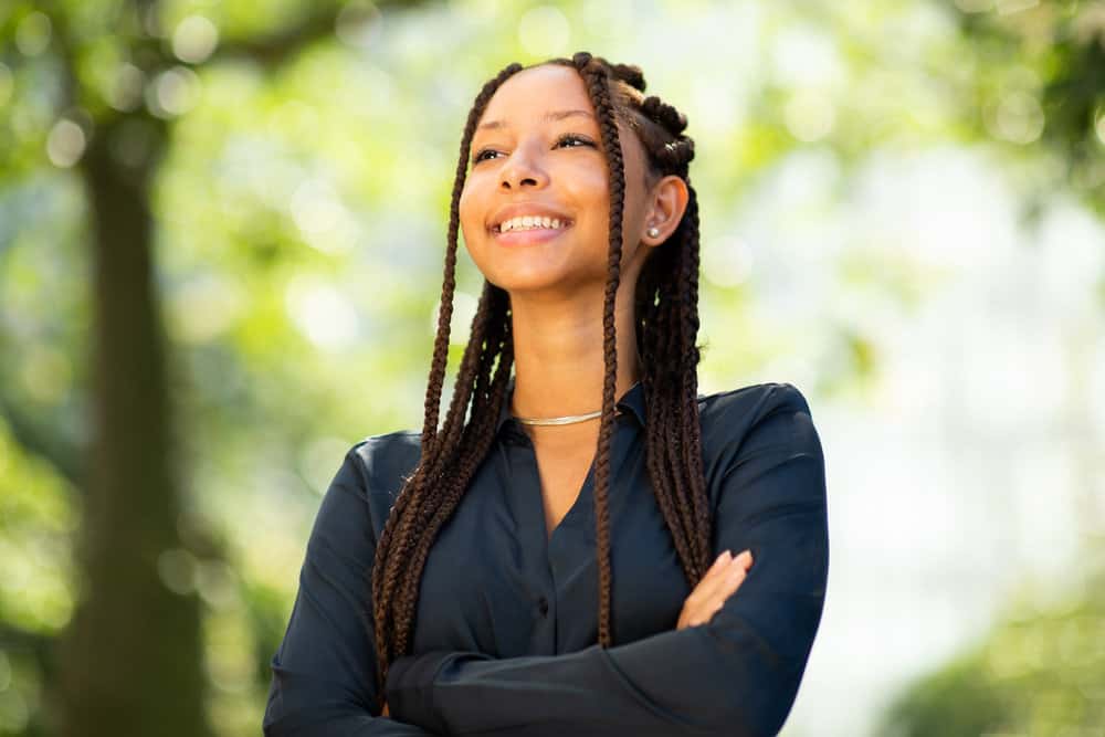 A lady with a great smile wearing a full head of braids twisted into a fun top-knot in the back with large cornrows.