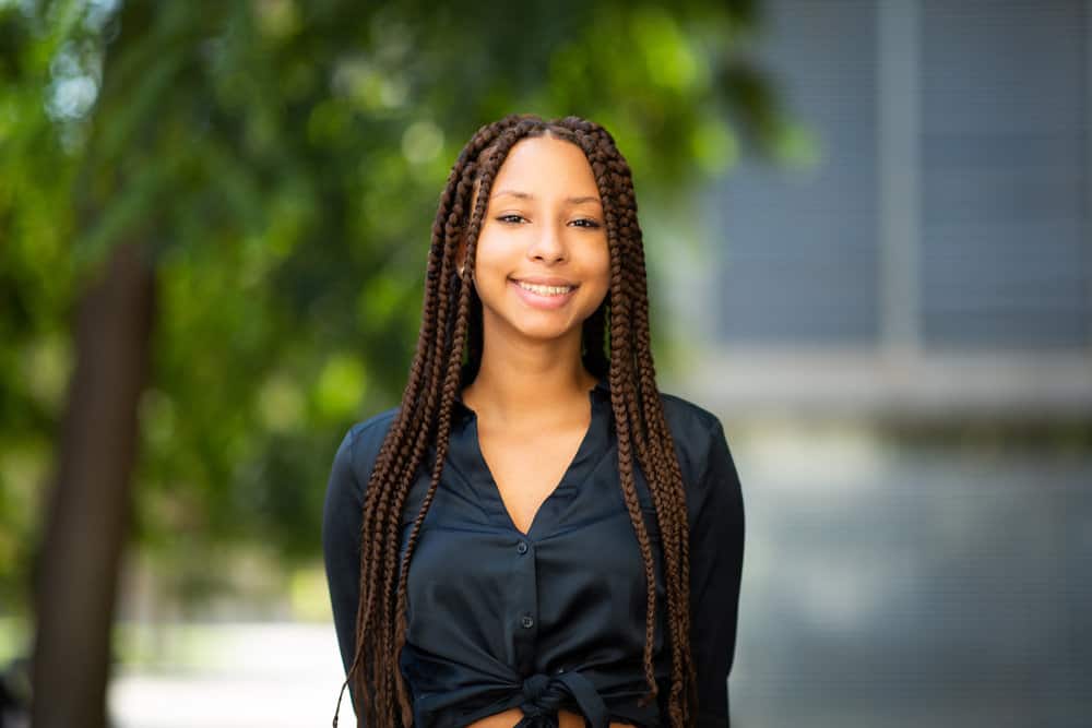 A stylish young African American woman looks like Alicia Keys or Tessa Thompson, wearing Havana twists.