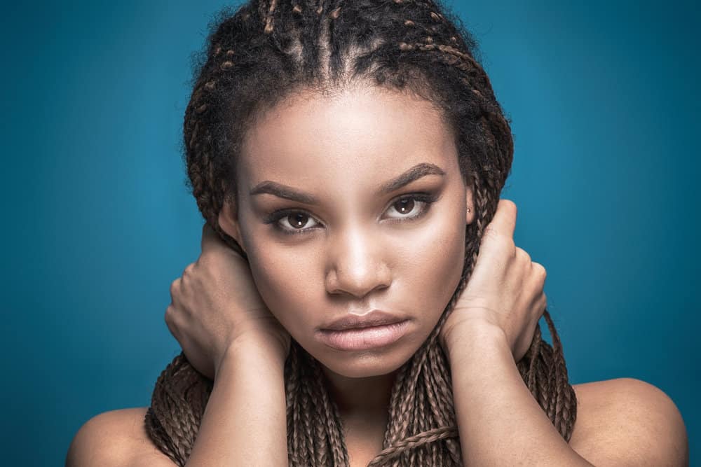 A lady wondering how much tribal braids cost while waiting at the salon for the traditional hairstyle to be installed.