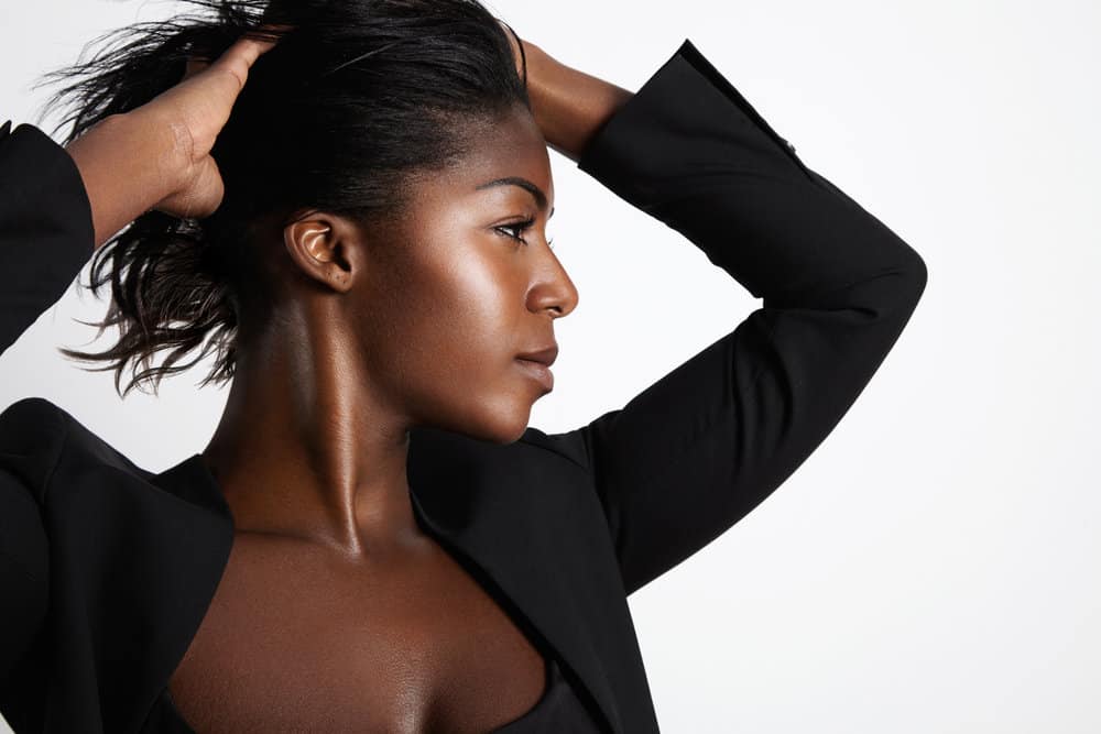 A dark skin black girl is wearing a straight hairstyle created with high heat and a stylish business suit.