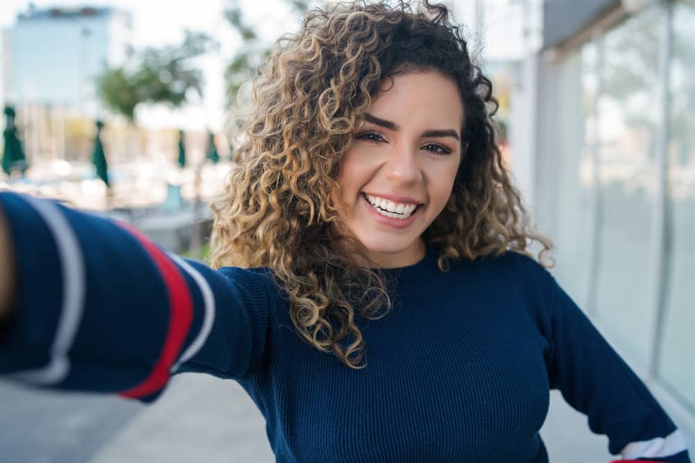 A young Latin female with beautiful curly hair is wondering why aging curly hair changes for many women.