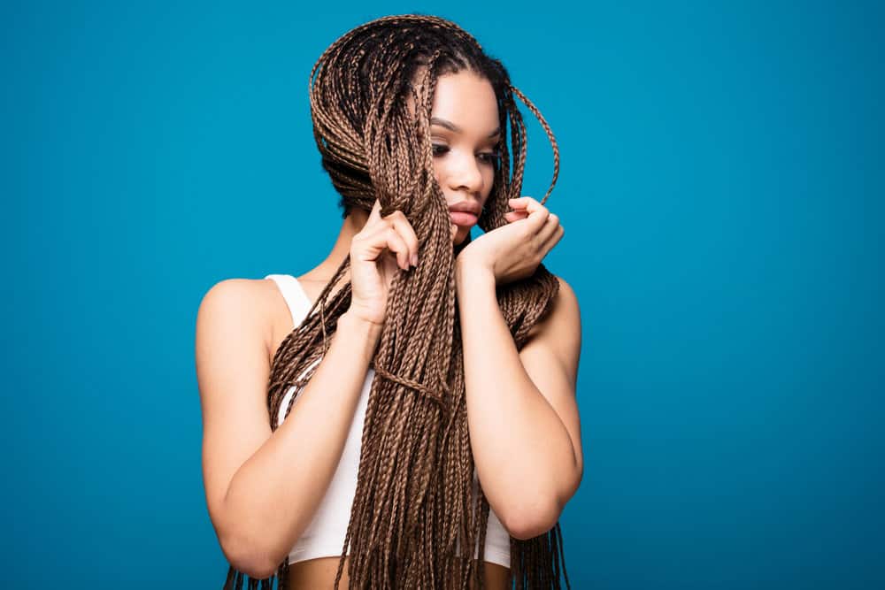A young black female is wearing Fulani braids - an adorable hairstyle for African women that want a Goddess braids-look.